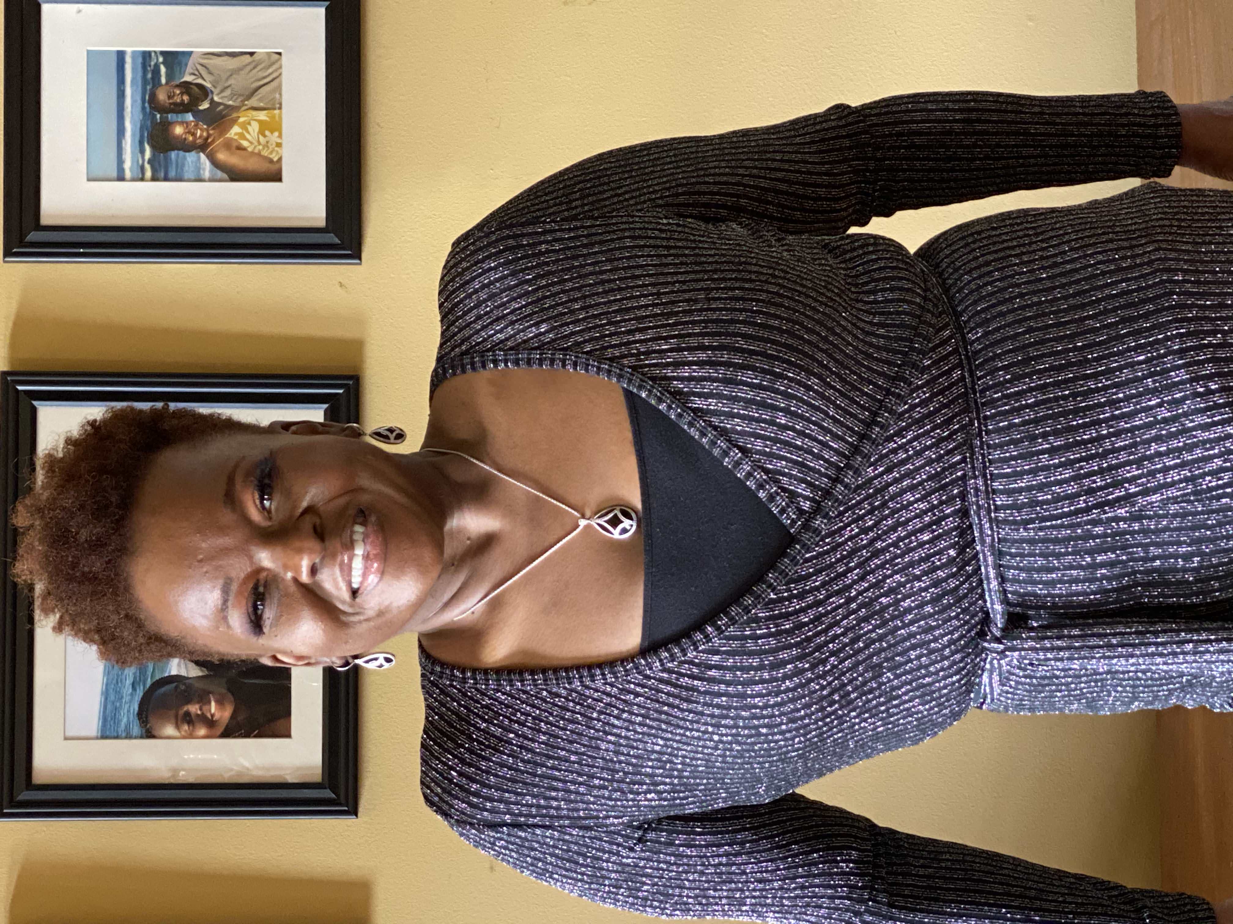 DeeDee Johnson smiling warmly, wearing a sparkling wrap dress and a teardrop pendant necklace